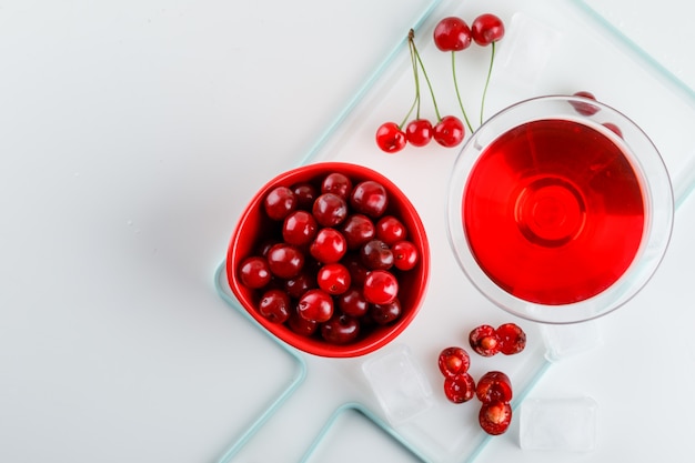 Kirschsaft mit Kirschen in einem Glas auf Weiß und Schneidebrett