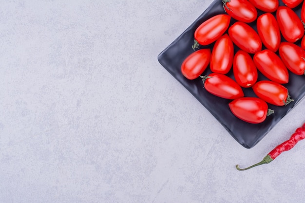 Kirschtomaten und roter Chili in einer schwarzen Platte.