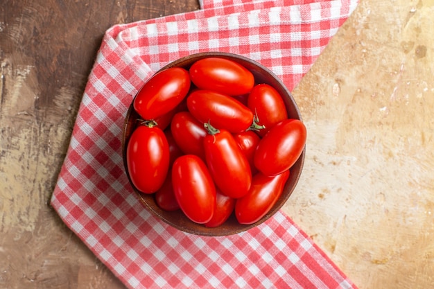 Kirschtomaten von oben in einer Holzschale ein Küchentuch auf bernsteinfarbenem Hintergrund