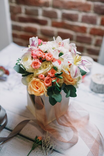 Kiste mit weissem und orangenem Bouquet steht auf Floristenarbeit ta