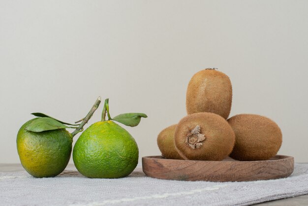 Kiwis und frische Mandarinen auf grauer Tischdecke.