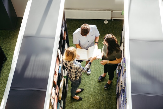 Klassenkameraden mit Buch in der Bibliothek