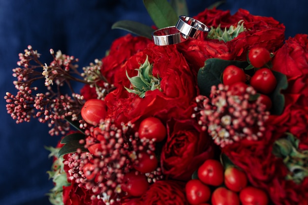 Klassische Eheringe aus Weißgold auf rotem Blumenstrauß