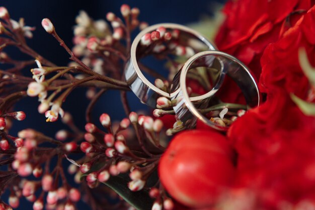 Klassische Eheringe aus Weißgold auf rotem Blumenstrauß