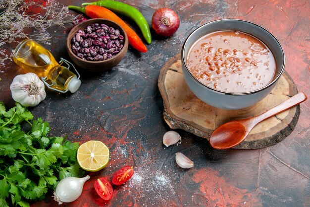 Klassische Tomatensuppe mit Ölflasche mit Lebensmitteln und Bohnen und einem Bündel grüner Zitronentomate auf gemischter Farbtabelle