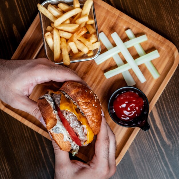 klassischer Cheeseburger mit Pommes Frites auf Holzbrett