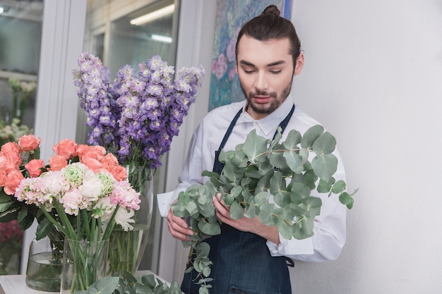 Kleinbetrieb. Männlicher Florist im Blumenladen. Dekorationen und Arrangements machen