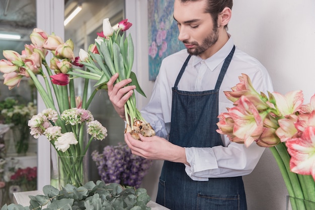 Kleinbetrieb. Männlicher Florist im Blumenladen. Dekorationen und Arrangements machen