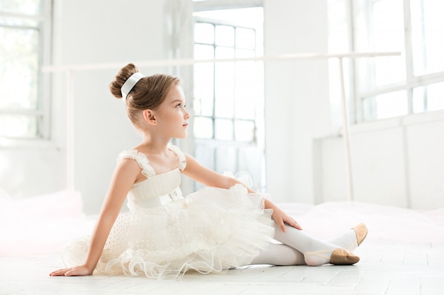 kleine Ballenpresse im weißen Tutu im Unterricht an der Ballettschule