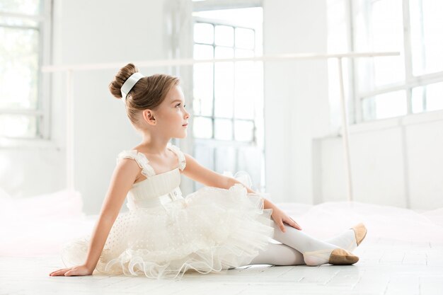 kleine Ballenpresse im weißen Tutu im Unterricht an der Ballettschule