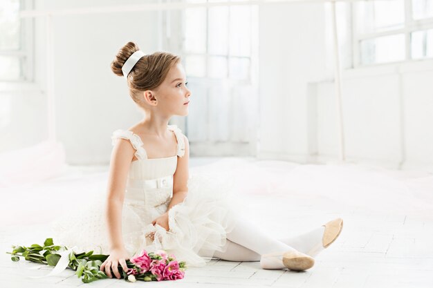 kleine Ballenpresse im weißen Tutu im Unterricht an der Ballettschule