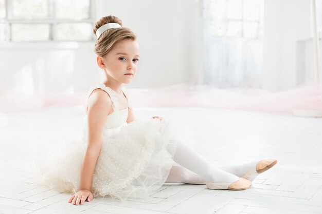 kleine Ballerina in weißem Tutu in der Ballettschule