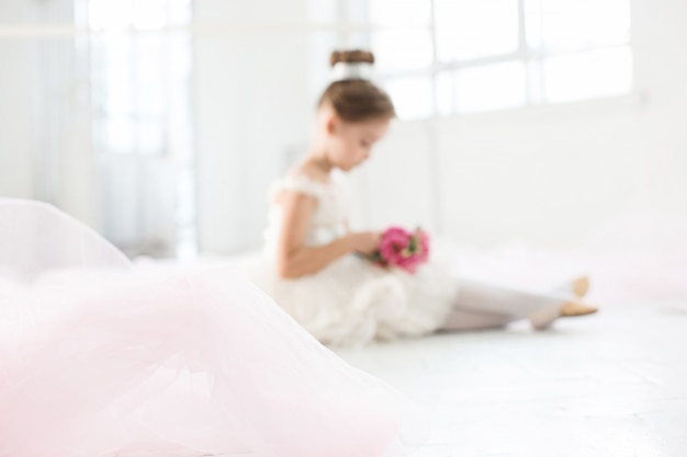 kleine Ballerina in weißem Tutu in der Ballettschule