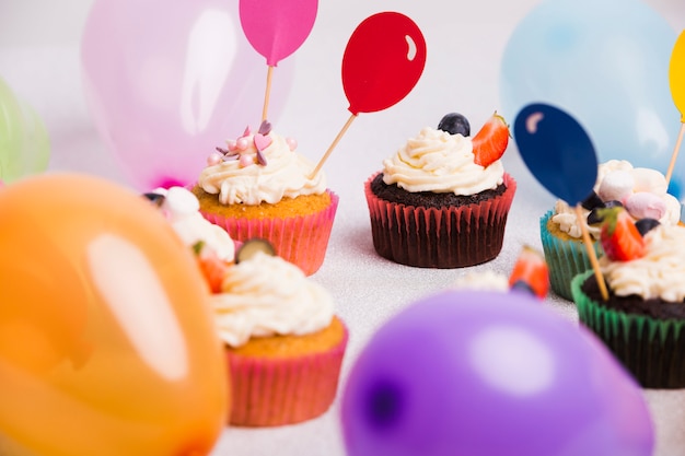 Kostenloses Foto kleine cupcakes mit luftballons auf leuchttisch