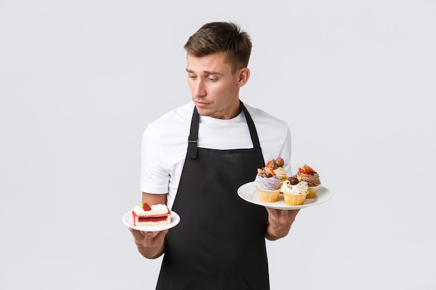 Kleine Einzelhandelsgeschäft-Cafés und Bäckerei-Konzept hübscher Kellner in schwarzer Schürze mit Blick auf...