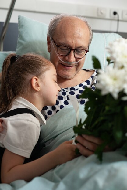 Kleine Enkelin umarmt älteren Großvater, der ihn in der Krankenstation besucht