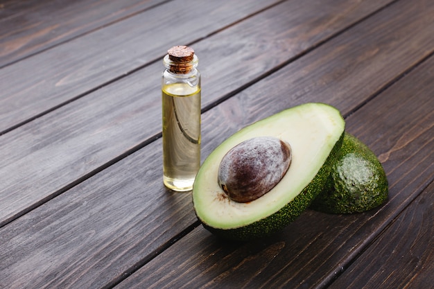 Kleine Flasche mit Öl und Avocado stehen auf dem Holztisch