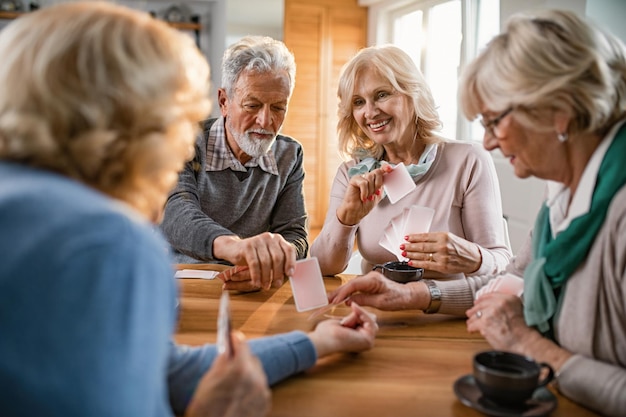 Kleine Gruppe reifer Freunde, die sich beim Kartenspielen zu Hause amüsieren