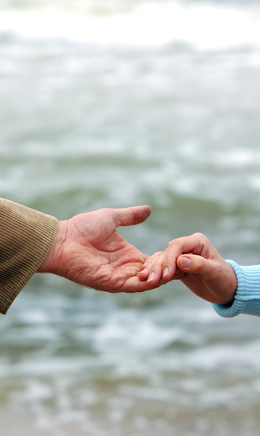 Kleine Hand mit einem Handschlag auf eine große Hand geben