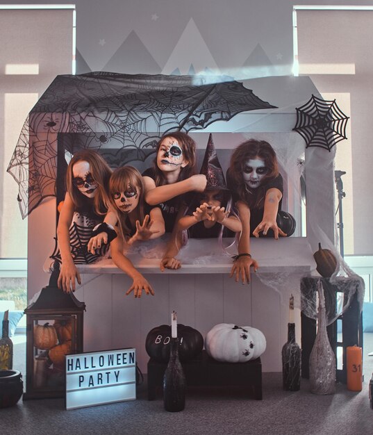 Kleine Heim-Halloween-Party mit Kids und Teens in gruseligen Rollenkreationen, wie Vampir, Hexe, Skelett.