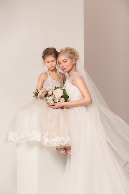 Kleine hübsche Mädchen mit Blumen in Brautkleidern gekleidet