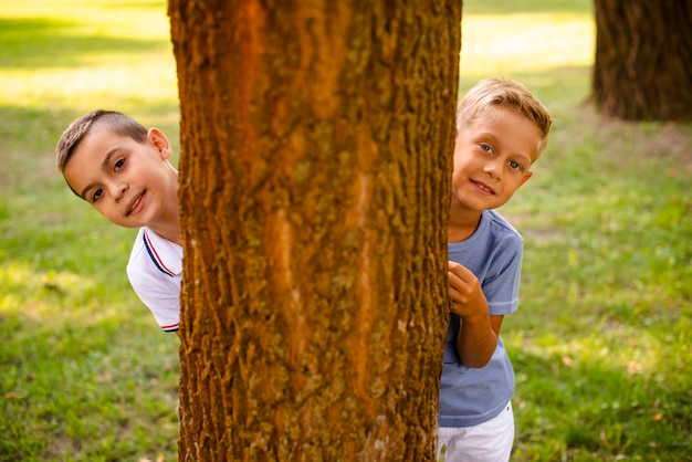 Kleine Jungen der Vorderansicht, die hinter einem Baum aufwerfen