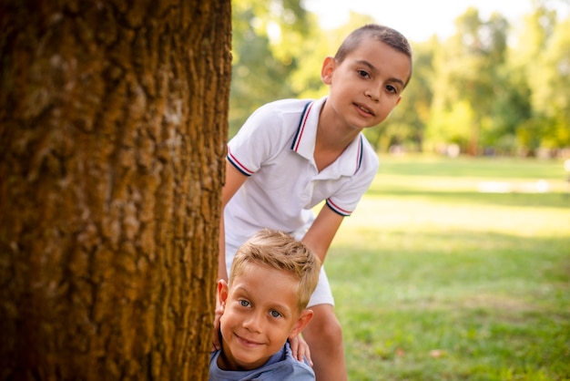 Kostenloses Foto kleine jungs posieren hinter einem baum