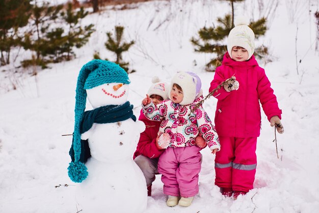 Kleine Kinder betrachten einen schönen Schneemann