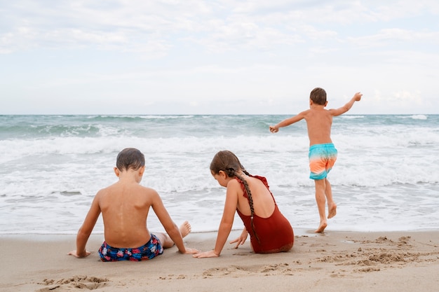 Kleine Kinder im Vollbild, die Spaß am Strand haben