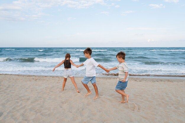Kleine Kinder im Vollbild, die Spaß am Strand haben