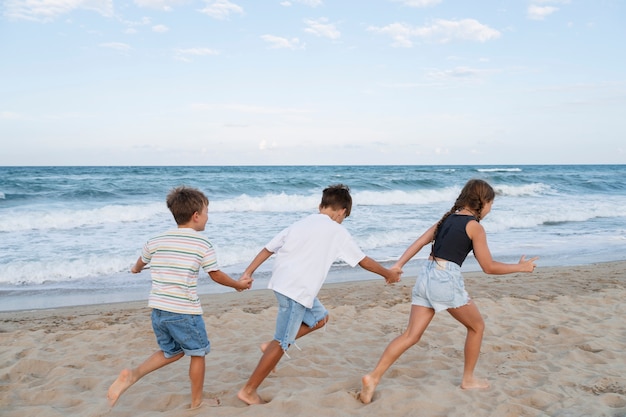 Kleine Kinder im Vollbild, die Spaß am Strand haben