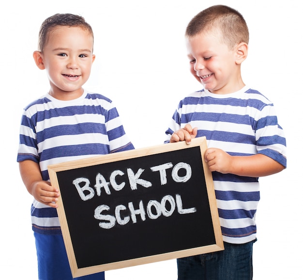 Kleine Kinder mit einer Tafel mit der Meldung lächelnd &quot;back to school&quot;