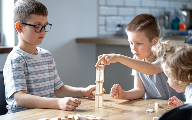 Kleine Kinder spielen zu Hause in der Küche ein Brettspiel mit Holzwürfeln.