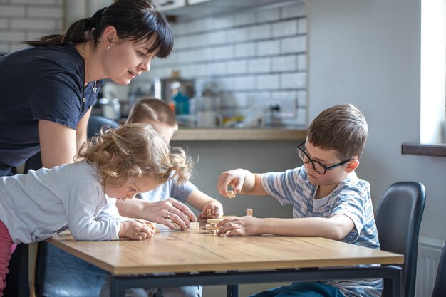 Kleine Kinder spielen zu Hause in der Küche mit Mama Brettspiel mit Holzwürfeln.