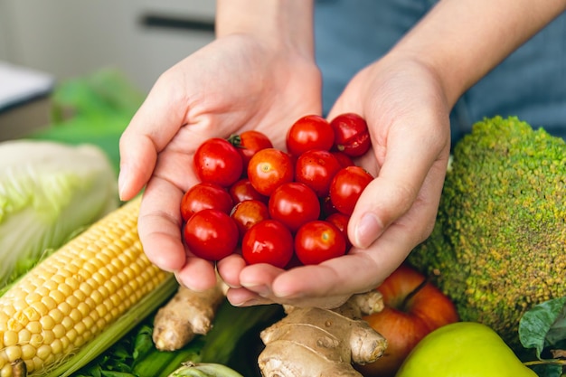 Kleine Kirschtomaten in den Händen der Frauen auf einem verschwommenen Hintergrund