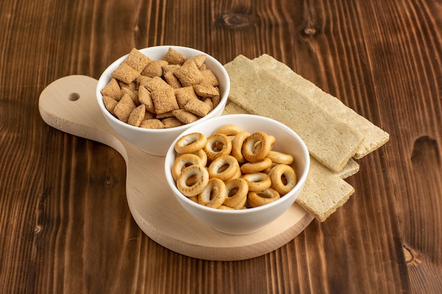 Kleine Kissenplätzchen der Vorderansicht mit Crackern auf dem braunen Schreibtisch