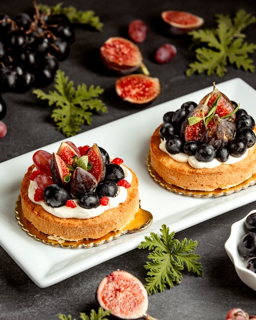 Kleine kuchen mit feigen blaubeeren und trauben dekoriert