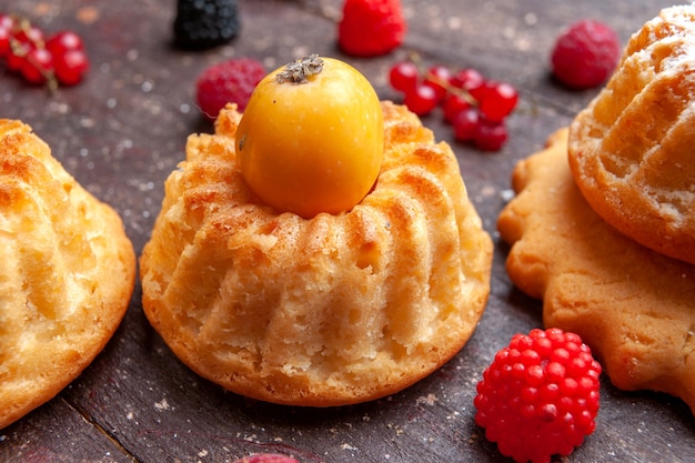 Kostenloses Foto kleine kuchen mit frischen früchten auf braunem obstbeeren-kuchen-keks-kuchen
