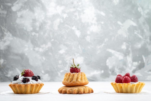 kleine leckere Kuchen mit Sahne und Beeren auf leichtem, Kuchen Keks Beerenfrucht süßer Zucker