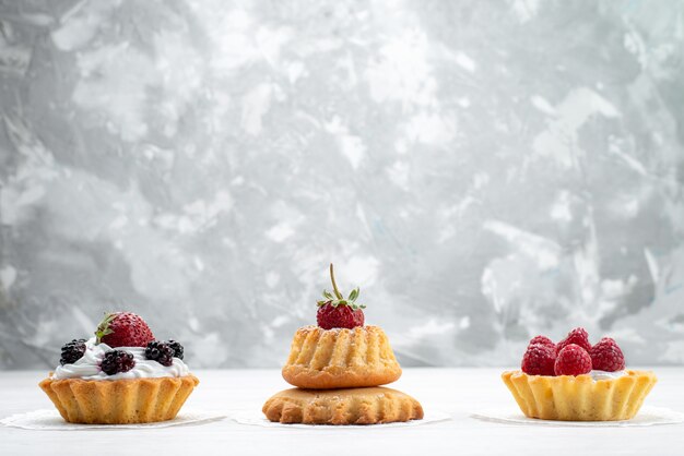kleine leckere Kuchen mit Sahne und Beeren auf leichtem, Kuchen Keks Beerenfrucht süßer Zucker