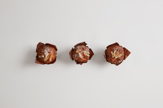 Kostenloses Foto kleine leckere süße muffins mit puderzucker bestreut auf weißer oberfläche. dessert zum tee trinken. vom konditor gebackene gourmet-süßwaren. junk food und ernährungskonzept