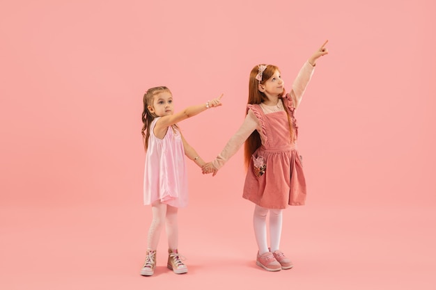 Kleine Mädchen, die auf rosa Wand zeigen