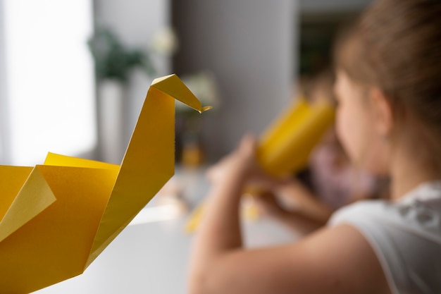 Kleine Mädchen, die zu Hause mit Origami-Papier spielen