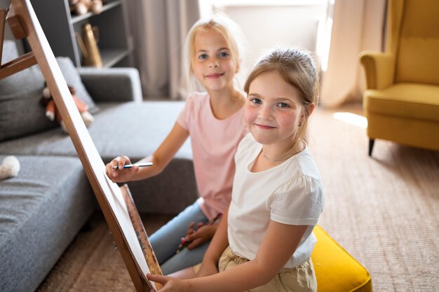 Kleine Mädchen, die zu Hause zusammen mit der Staffelei zeichnen