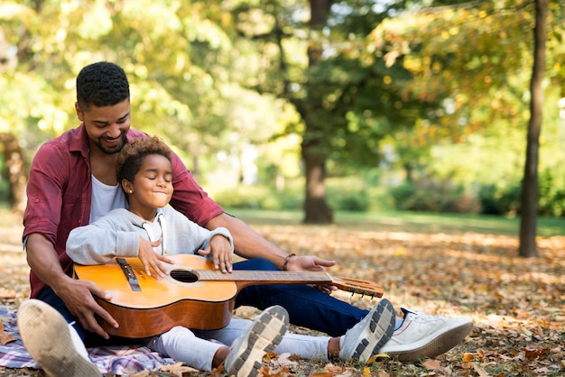 Kleine mädchen in vätern umarmen lernen, gitarre zu spielen