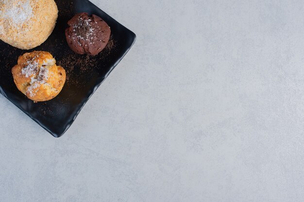 Kleine Platte mit verschiedenen Cupcakes auf Marmoroberfläche