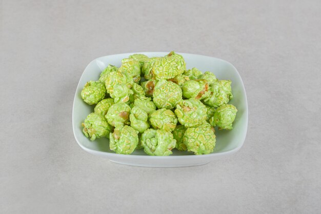 Kleine Schüssel grünes kandiertes Popcorn auf Marmortisch.