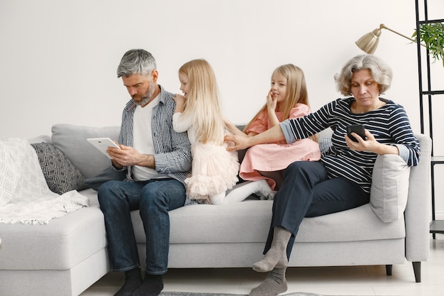 Kleine Schwestern, die mit Großeltern auf der Couch sitzen