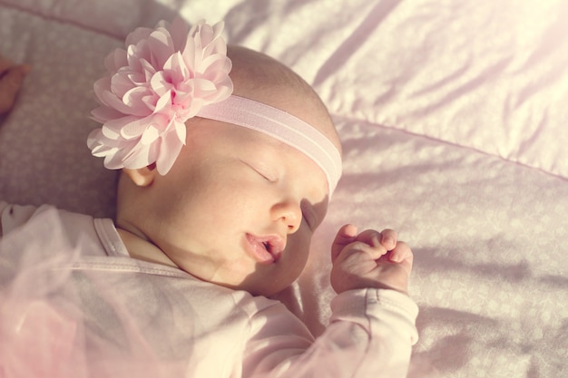 Kostenloses Foto kleine süße baby mädchen liegt und schläft in ihrem bett, hält es hand auf mund. schönes sonnenlicht horizontal.