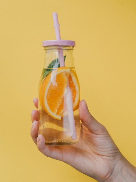 Kleiner Behälter für Natursaft mit Strohhalm in der Hand